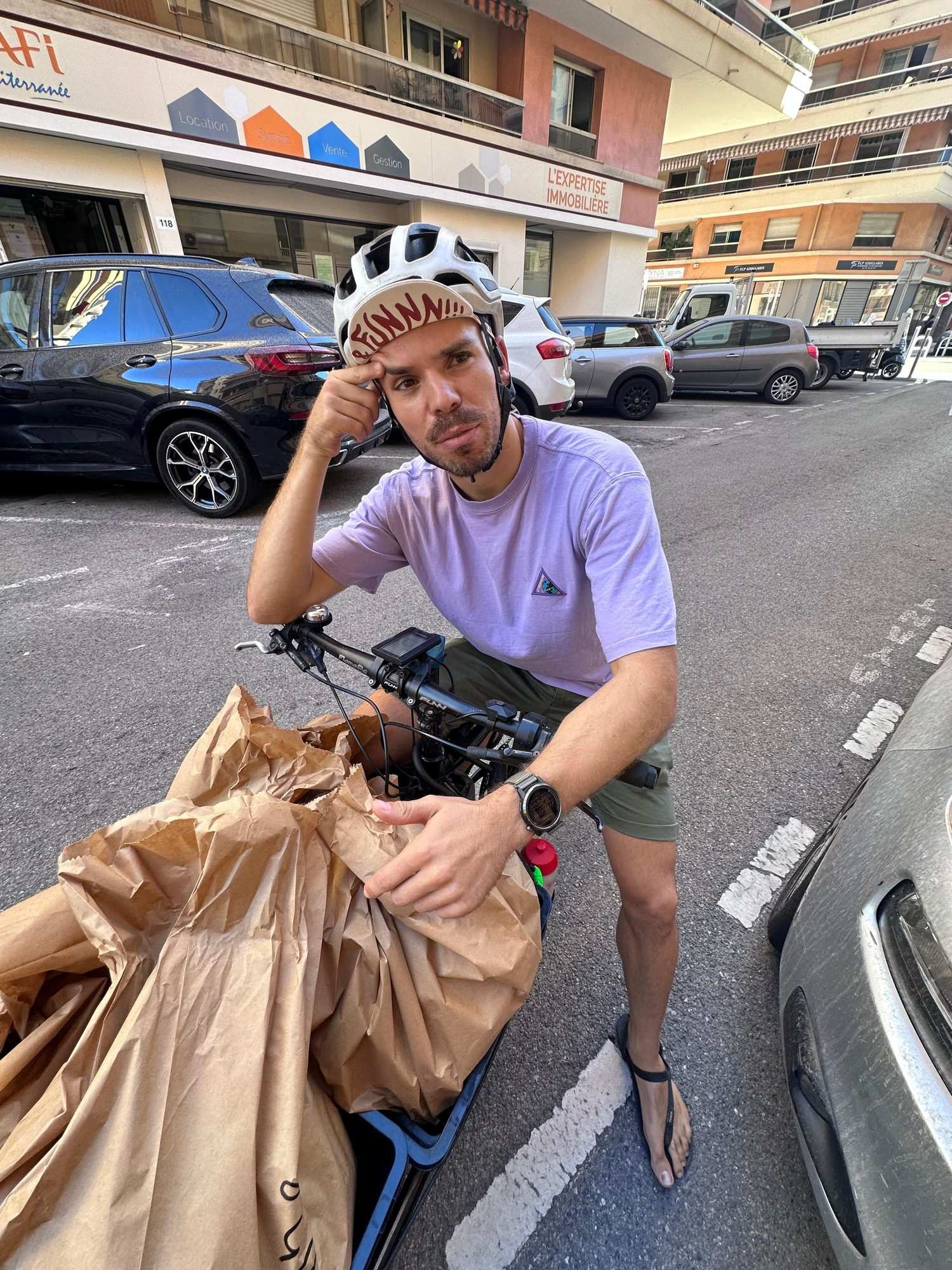 Paul sur son vélo cargo chargé de sacs de livraison, dans une rue de Nice